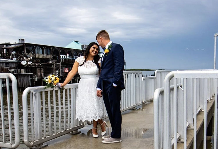 Couple standing on a dock with a cloudy sky background